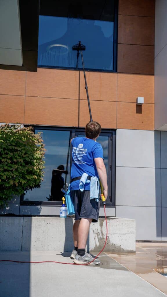 A technician using a specialized low-pressure applicator to evenly coat vinyl siding with a biodegradable soft wash solution designed to kill algae and mold.