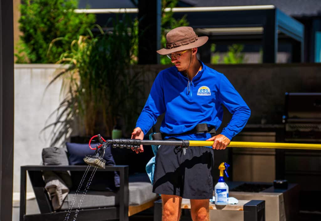 A Clear View Cleaning technician carefully covering delicate garden plants and taping off electrical outlets on a home's exterior to ensure total safety during the cleaning process.